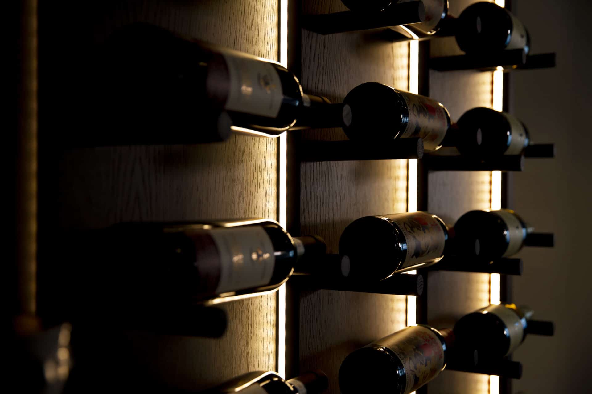 Närbild på vinflaskor med belysning mörkbetsad ek